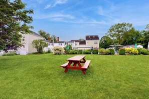 A picnic table in a grassy area with houses in the background.