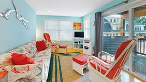 A living room with a sofa, chairs, a TV, and a balcony with a view. - Cheerful condo one mile from Ogunquit Beach with a pool - near dining (Wells)