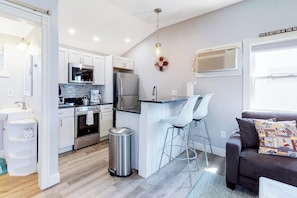 A compact kitchen with modern appliances, a dining area with bar stools, and a cozy seating area with a sofa.