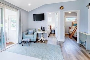 A room with a sofa, a TV, a small table, and a staircase leading to a loft bed area.