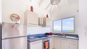 Uma cozinha moderna com geladeira de aço inoxidável, forno embutido, janela com vista e ventilador de teto.