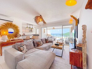 Ein modernes Wohnzimmer mit einem Ecksofa, einem Couchtisch und Blick auf den Ozean.