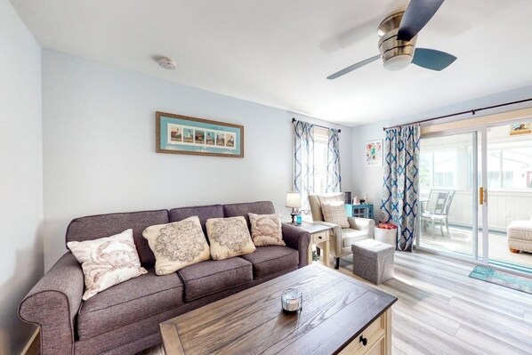 Sala de estar com sofá, mesa de centro e ventilador de teto.