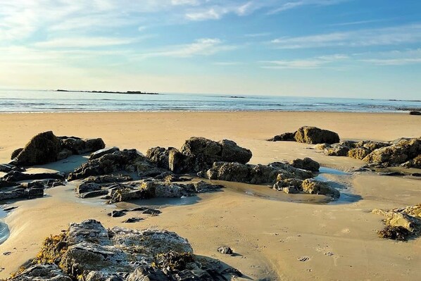 A beach with large rocks and a clear sky.