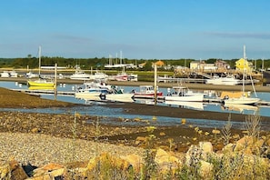 A marina with boats docked, a building with a yellow roof, and a rocky shoreline.