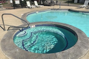 A swimming pool with a tiled edge, a metal ladder, and lounge chairs around the perimeter.