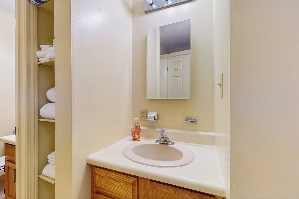 A bathroom with a sink, mirror, and towel storage.