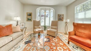 Un salon comprenant un canapé, des fauteuils, une table basse et un tapis à motifs.