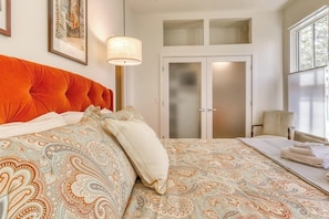 Un dormitorio con una cama grande, un armario, una silla y una ventana.