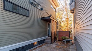 Une ruelle étroite bordée de maisons, avec une petite construction en bois, un banc et un bac à fleurs.