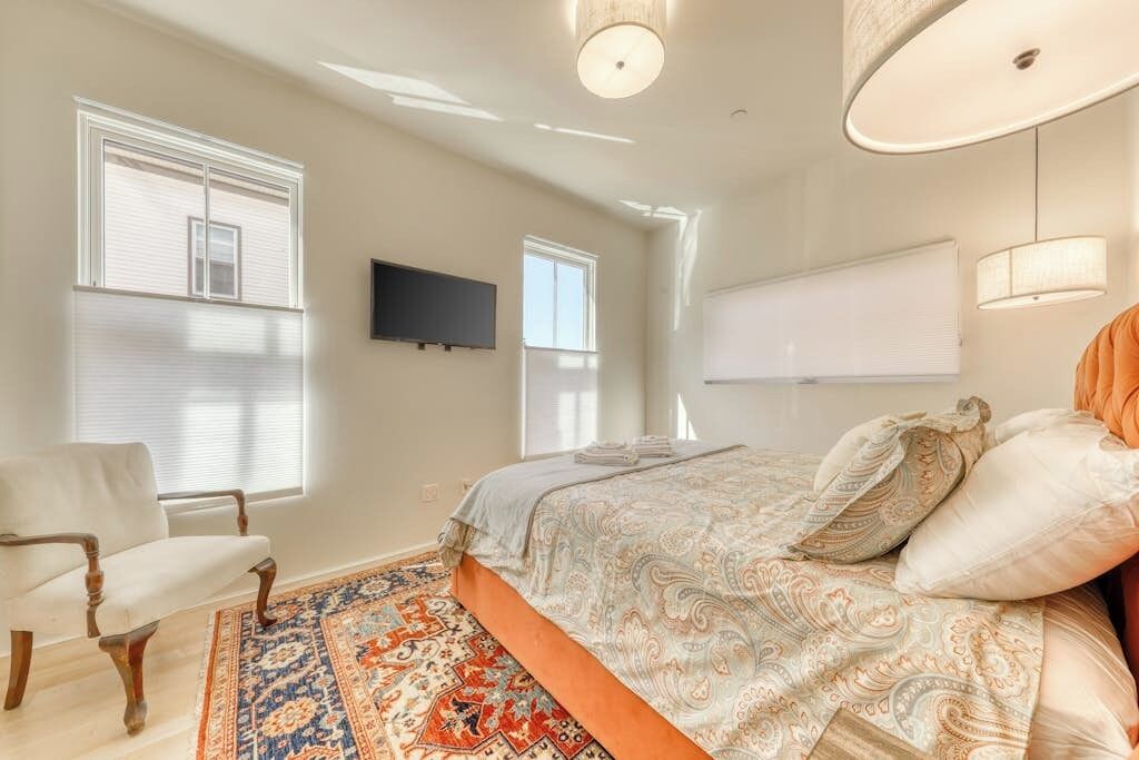 Een slaapkamer met een bed, een stoel, een televisie en een raam.