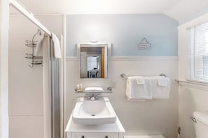 A bathroom with a sink, mirror, towel rack, and a sign on the wall.