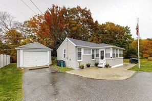 Ein zweistöckiges Haus mit Garage, Veranda und Fahnenmast.