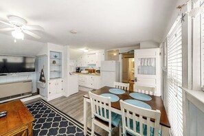 A compact living space with a dining area, kitchenette, and a TV in the living room.