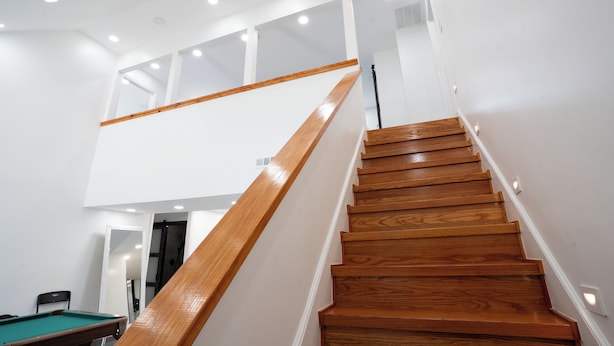 A wooden staircase with a glass railing leading to an upper level. - Glam Luxe Modern Stay Near Uptown Charlotte (Charlotte)
