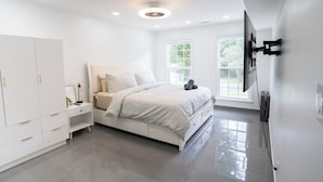 A modern bedroom with a bed, wardrobe, bedside table, and a TV mounted on the wall. - Glam Luxe Modern Stay Near Uptown Charlotte (Charlotte)