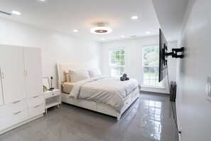A modern bedroom with a bed, wardrobe, bedside table, and a TV mounted on the wall.