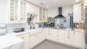 A modern kitchen with white cabinetry, a black range hood, and a hexagonal tile backsplash. - Glam Luxe Modern Stay Near Uptown Charlotte (Charlotte)