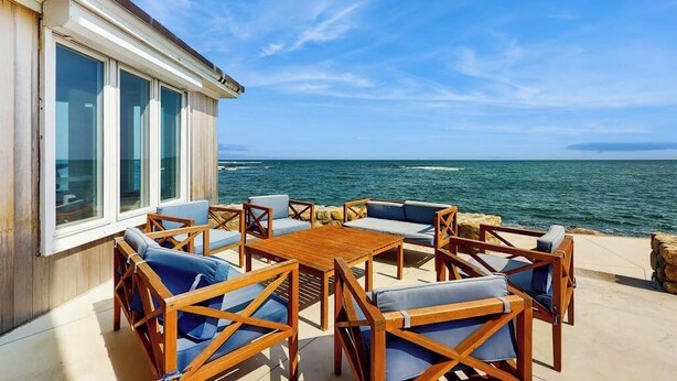 A patio with wooden furniture and a view of the sea. - Coastal gem on the water with beach access, gorgeous views & spacious layout (Wells)