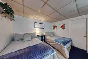 Ein Zimmer mit zwei Betten, einer Wandleuchte, einem gerahmten Zitat und zwei Sonnenbildern.