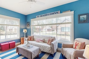 A room with a blue wall, a large window, a sofa, a chair, and a sign that reads 'NO RESERVATIONS'.