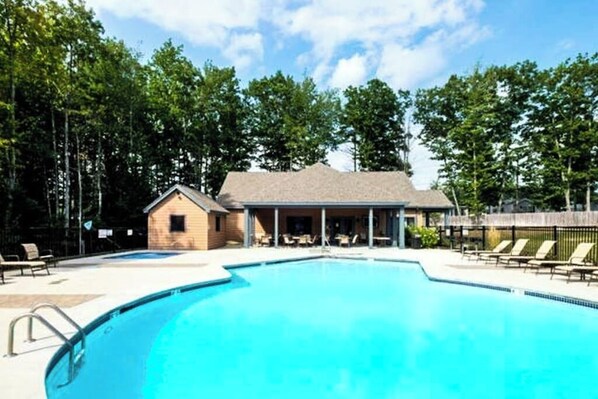 Une piscine avec des chaises longues et un petit bâtiment doté d’une véranda.