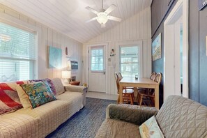 A cozy room with a bed, a dining table, and chairs. - Cute cottage with screened porch & shared pool - walk to Ogunquit Beach (Wells)