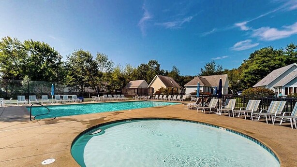 Una piscina con sillas de descanso y un área junto a la piscina.