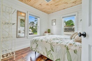 Ein Schlafzimmer mit Bett, Fenstern und Blick ins Freie.