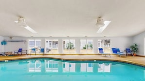 An indoor swimming pool with clear glass walls, blue lounge chairs, and ceiling fans. - Inviting condo with high-speed WiFi and shared indoor pool - two miles to beach (Wells)