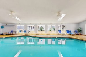 An indoor swimming pool with clear glass walls, blue lounge chairs, and ceiling fans. - Inviting condo with high-speed WiFi and shared indoor pool - two miles to beach (Wells)