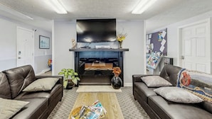 A living room with two leather sofas, a coffee table, a fireplace, and a flat-screen TV. - Inviting condo with high-speed WiFi and shared indoor pool - two miles to beach (Wells)