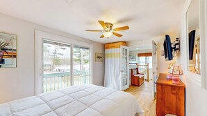 Un dormitorio con cama, ventilador de techo, ventana, puerta, escritorio y silla.