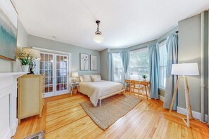 Ein Schlafzimmer mit Bett, Nachttisch, Lampe und Blick ins Freie.