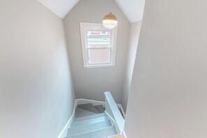 Eine Treppe führt zu einer Zwischenebene mit einem Fenster und einer Pendelleuchte.