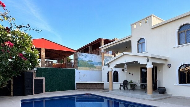 A swimming pool with a patio area, a covered outdoor seating area, and a building with a mural. - Special house to spend a pleasant time (El Caballito)
