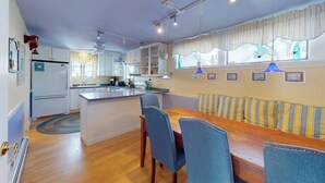 Une cuisine avec un îlot central, une table à manger avec des chaises et une fenêtre avec des rideaux.