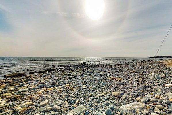 A rocky beach with pebbles and a clear sky.