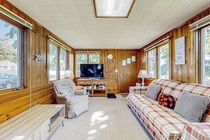 Une pièce confortable avec une télévision, des murs en bois, un canapé et un fauteuil.