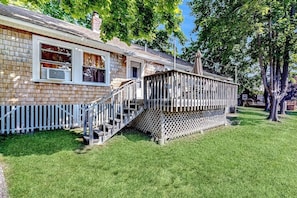 Une maison dotée d’une terrasse en bois, d’un escalier menant à un porche couvert et d’une façade en briques.