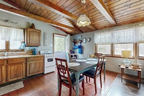 Una cocina rústica con armarios de madera, una mesa de comedor con sillas, una araña y vistas al exterior.