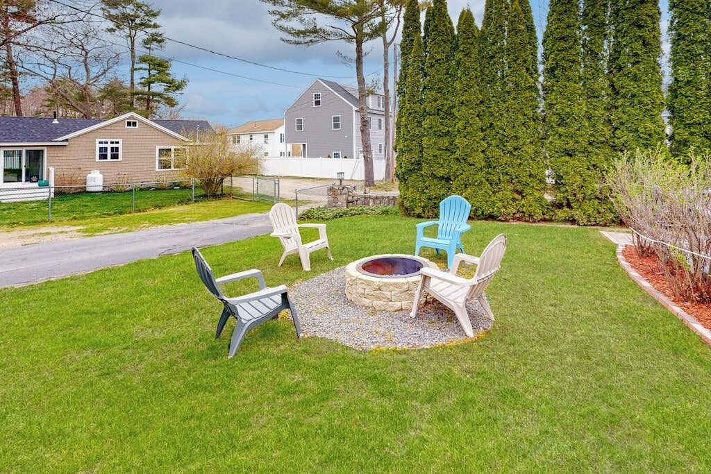 Un jardin avec un foyer en pierre et quatre fauteuils Adirondack.