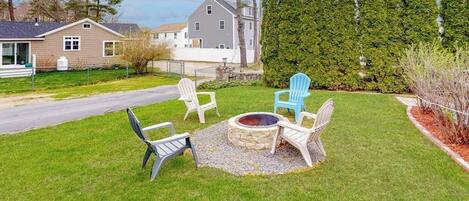 Un jardin avec un foyer en pierre et quatre fauteuils Adirondack.