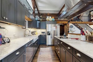 Eine moderne Küche mit dunklen Schränken, einem Edelstahlkühlschrank und einer Marmorarbeitsplatte.