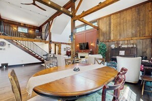 Ein geräumiges Loft mit großem Holztisch, einer Treppe und einem Kamin.