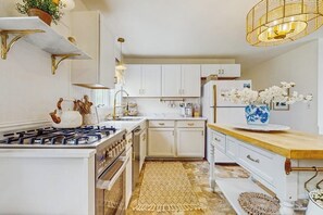 A kitchen with white cabinets, a gas stove, and a wooden countertop.