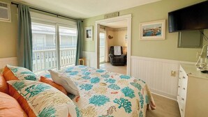 A bedroom with a bed, a chair, a television, and a view of the outside. - Coastal luxury condo steps from Wells Beach w/ AC, WiFi & full kitchen (Wells)