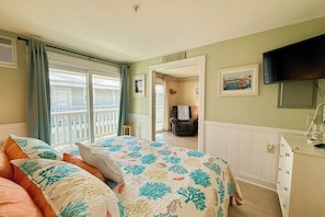 Ein Schlafzimmer mit Bett, Sessel, Fernseher und Blick ins Freie.
