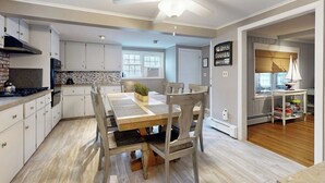 Uma cozinha moderna com armários brancos, uma mesa de jantar de madeira e um ventilador de teto.