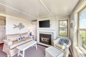 A living room with a sofa, a chair, a table, a fireplace, and a television. - Beautiful waterfront house & cottage w/ a firepit - walk to the beaches & town (York)
